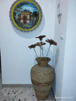 a vase with flowers in it next to a plate at La casa di Nanà IL BAGLIO in Palermo