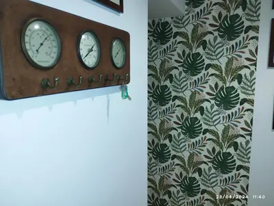 a clock hanging on a wall with a floral wallpaper at La casa di Nanà IL BAGLIO in Palermo