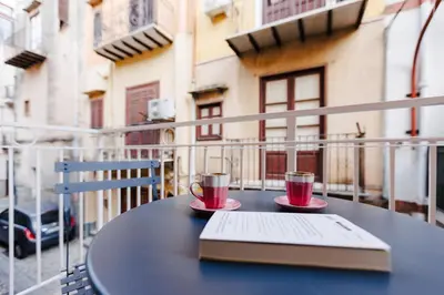 a table with two cups and a book on a balcony at Ciao Sycylia Apartments in Carini
