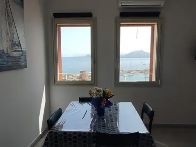 a table with a vase of flowers on it with two windows at RineddaHouse Arenella - Vista Mare Panoramica a Palermo con Parcheggio privato in Palermo