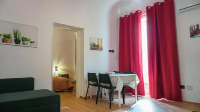 a dining room with red curtains and a table with chairs at Ospiti a casa mia in Palermo