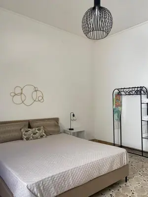 a white bedroom with a bed and a chandelier at Licia's home in Palermo