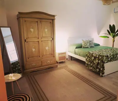 a bedroom with a bed and a wooden cabinet at L'Arco Verde San Nicola l'Arena in Trabia