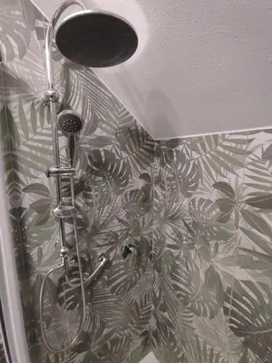 a shower in a bathroom with a plant pattern on the wall at L'Arco Verde San Nicola l'Arena in Trabia