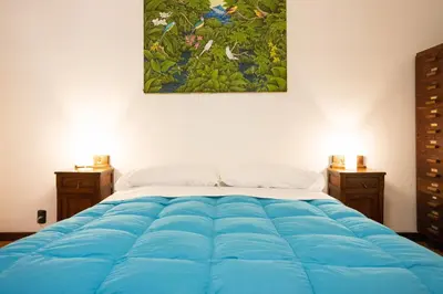 a bedroom with a large blue bed with a painting on the wall at Casa Ibiscus in Mondello