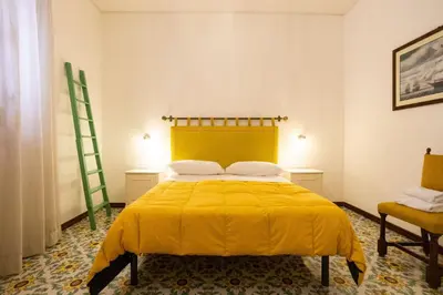 a bedroom with a yellow bed and a chair at Casa Ibiscus in Mondello