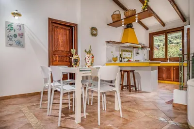 a kitchen with a white table and chairs at Villa Miceli con piscina privata in Scopello