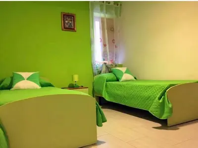 a green bedroom with two beds and a couch at Appartamento Casa Trento in Castellammare del Golfo