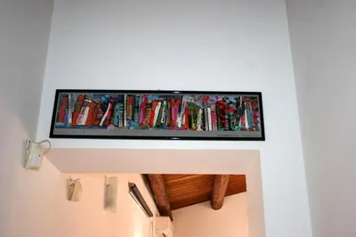 a tv hanging on a wall with books at Casa Bellini in Palermo