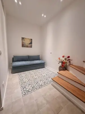 a living room with a blue couch and stairs at Casa Rosa Castellammare del Golfo in Castellammare del Golfo