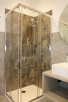 a shower with a glass enclosure next to a sink at ALLUMARO HOUSE in Castellammare del Golfo