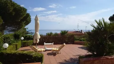 a patio with two chairs and an umbrella and a table at Villa Chifeci Scopello - Appartamento Rosso in Scopello