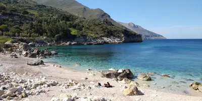 a group of people sitting on a beach near the water at Villa Chifeci Scopello - Appartamento Verde in Scopello