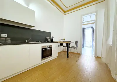 a kitchen with white cabinets and a table in it at Solemar Sicilia - Casa Markiz in Palermo