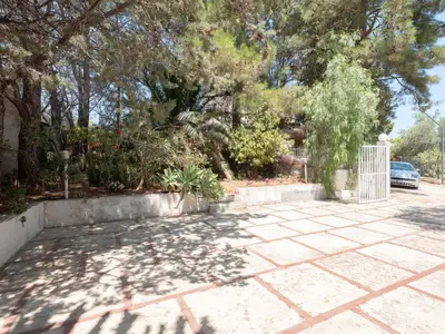 a driveway with a gate in a yard with trees at [Baia di Guidaloca] Villino Scopello Free Parking in Scopello