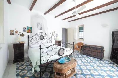 a bedroom with a bed and a table and a chair at Casetta Bianca Sant'Elia in Porticello