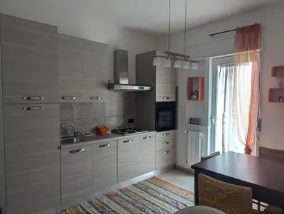 a kitchen with gray cabinets and a table and a window at Rosalba apartments - cheap and characteristic in Palermo