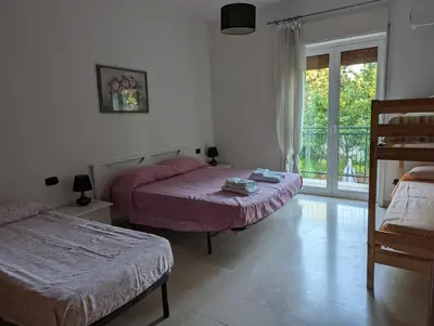 a bedroom with two beds and a window with a balcony at Rosalba apartments - cheap and characteristic in Palermo