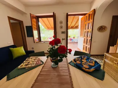 a living room with a table with a vase of red flowers at Casa a Mare La Stalletta in Palermo
