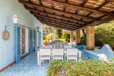 a patio with a table and chairs on a blue floor at Mille e Una Notte By Domus Sicily in Mondello