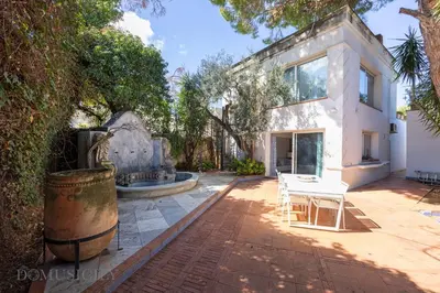a white house with a fountain and a table and chairs at Mille e Una Notte By Domus Sicily in Mondello