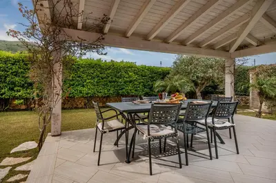 a table and chairs sitting under a pergola at Villa Jacqueline con piscina privata 8 posti letto in Scopello