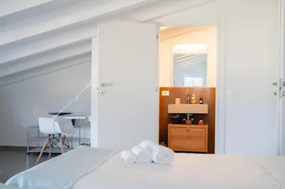 a bedroom with a bed with white sheets and a chair at Villa Majestatis con piscina privata in Scopello
