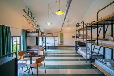 a room with bunk beds and a table and chairs at Ostello Bello Palermo in Palermo