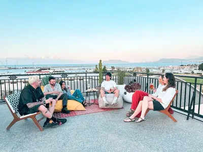 a group of people sitting on chairs on a balcony at Ostello Bello Palermo in Palermo