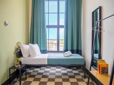 a bedroom with a bed and a window with blue curtains at Ostello Bello Palermo in Palermo