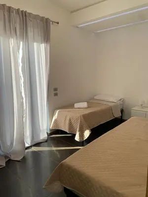 a room with two beds and white curtains at Villa Rubino in Isola delle Femmine