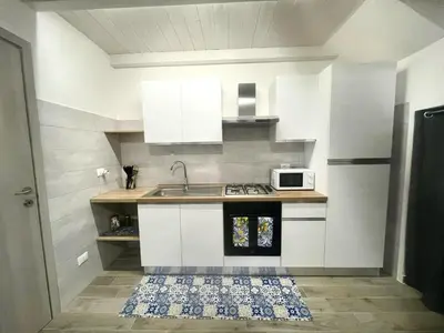 a kitchen with white cabinets and a sink and a microwave at Silvia's House in Castellammare del Golfo
