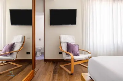 a bedroom with two chairs and a mirror at Verosicily Villa Barcellona in Terrasini