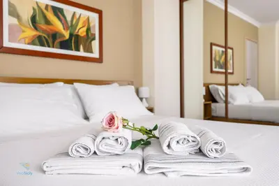 a white bed with towels and a rose on it at Verosicily Villa Barcellona in Terrasini
