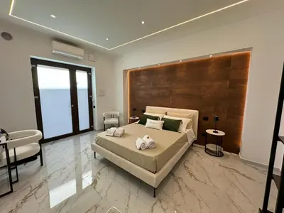 a bedroom with a large bed with a large wooden headboard at FLA' Suite Deluxe in Terrasini