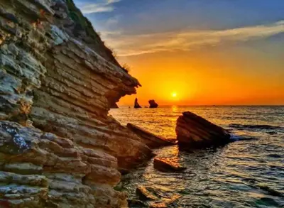 a sunset over the ocean with rocks in the water at FLA' Suite Deluxe in Terrasini