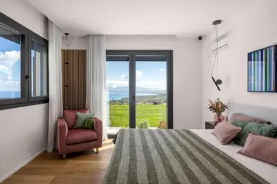 a bedroom with a bed and a chair and a window at Villa Adler Nature&Relax in Scopello