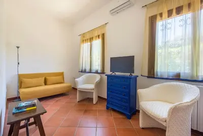 a living room with a couch and a tv and chairs at Villetta Milù in Palermo