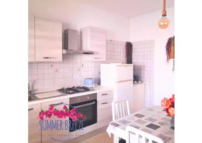 a kitchen with white appliances and a table with a dining room at Summer Breeze Apartments in Trappeto
