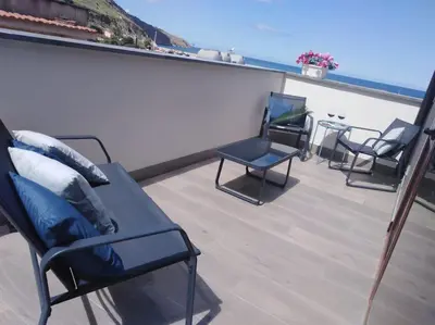 a balcony with chairs and a table and the ocean at A 2 passi dal castello ,appartamento con veranda in Castellammare del Golfo