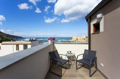 a balcony with two chairs and a table on a building at A 2 passi dal castello ,appartamento con veranda in Castellammare del Golfo