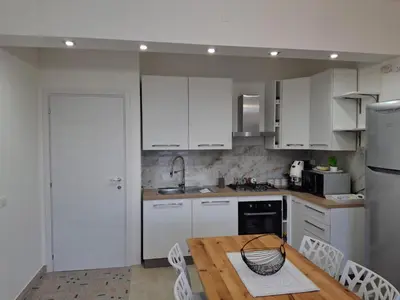 a kitchen with white cabinets and a wooden table at Ricky House in Palermo