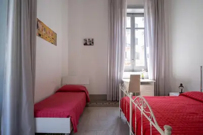 two beds in a room with red sheets at ROME 118 intero appartamento in Palermo
