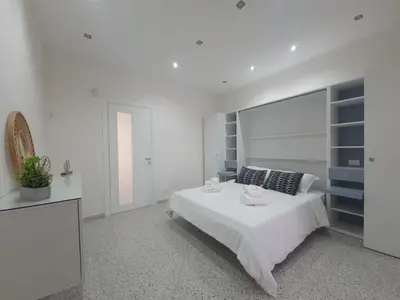 a white bedroom with a large white bed and shelves at Private House 14 Palermo in Palermo