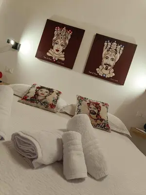 a white bed with four pictures on the wall at Calatafimi Rocca Home in Palermo