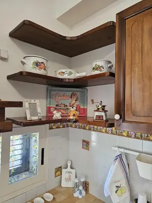 a kitchen with wooden shelves on the wall at Nika Holiday Home in Casteldaccia