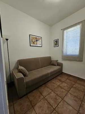 a couch in a living room with a window at Nika Holiday Home in Casteldaccia
