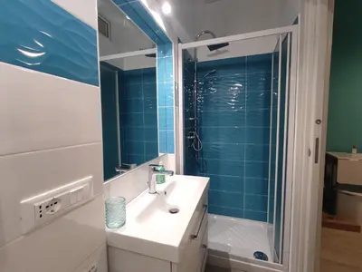 a bathroom with a sink and a shower with blue tiles at Casa vacanze Haliotis in Isola delle Femmine