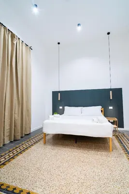 a bedroom with a white bed with a black headboard at Picciridda Rooms in Palermo