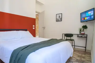 a bedroom with a white bed and a tv on the wall at Picciridda Rooms in Palermo